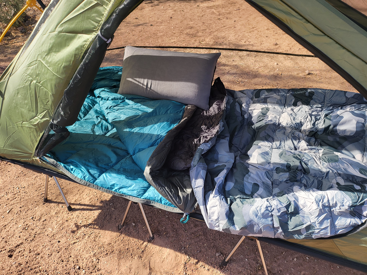My moto camping sleeping setup, including Night Cat Camping Cot Tent, Kelty Galactic 30 sleeping bag, Get Out Gear camping blanket, and Klymit camping pillow